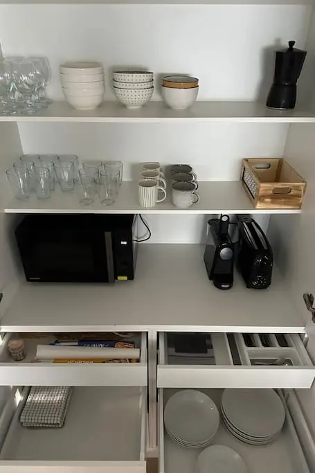 Kitchen cupboards with crockery, glasses and appliances at San Blas Stay Alicante