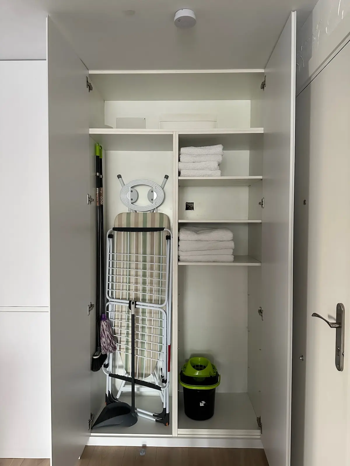 Utility cupboard with ironing board and cleaning equipment at San Blas Stay Alicante